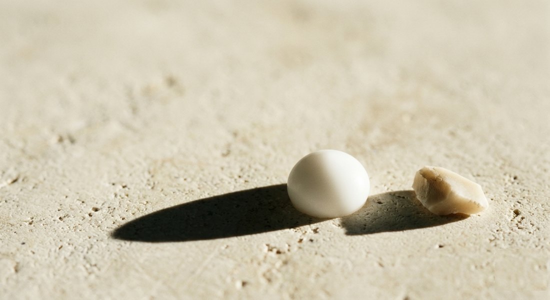 A drop of white resin beside a ceramic shard on pale stone