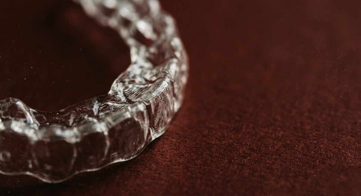 A clear bio. retainer on a deep oxide-red ground